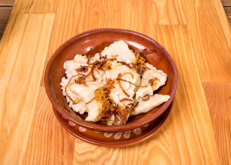 Traditional russian dumplings vareniki with fried onion. Located on wooden table background.の写真素材