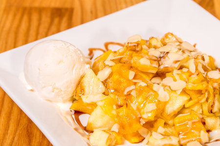 Delicious fried banana dessert with grated white chocolate and ice cream scoop. Plate located on...