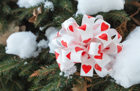 Bow with hearts as a christmas decoration on pine tree branch. Macro. Can be used as a whole background.の写真素材