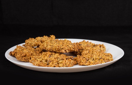 Plate with oatmeal cookies. Located on black textile tablecloth background.の写真素材