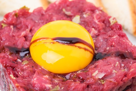 Delicious steak tartare covered with soya sauce with egg yolk and sauce. Macro. Photo can be used as a whole background.の写真素材