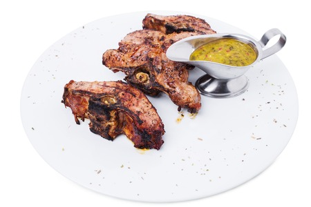 Delicious grilled lamb meat fillet on bones with spicy herb sauce. Isolated on a white background.の写真素材