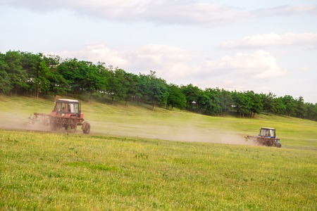 Two tractors in the field at nice sunny day in july. Photo can be used as a whole background.の写真素材