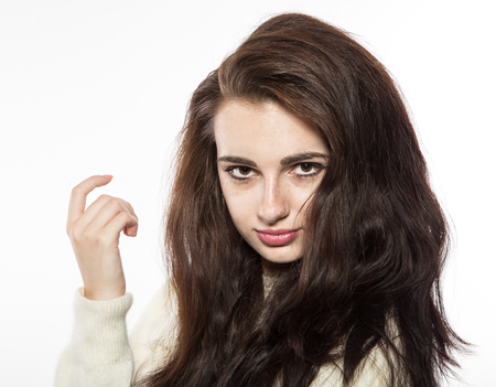 Portrait of smiling beautiful brunette model with freckles and long hair in yellow sweater. Isolated on a white background.の写真素材