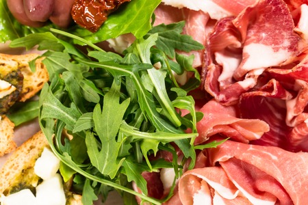 Traditional tuscan antipasto platter with cold cuts and fresh arugula. Macro shot. Photo can be used as a whole background.の写真素材