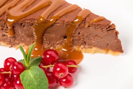 Delicious caramel cake with red currant glazed with chocolate cream. Macro. Photo can be used as a whole background.の写真素材