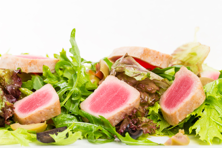 Grilled tuna fillet on fresh salad mix with sliced olives and pesto sauce. Macro. Photo can be used as a whole background.の写真素材