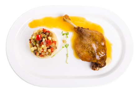 Duck leg confit with couscous and baked vegetables. Isolated on a white background.の写真素材
