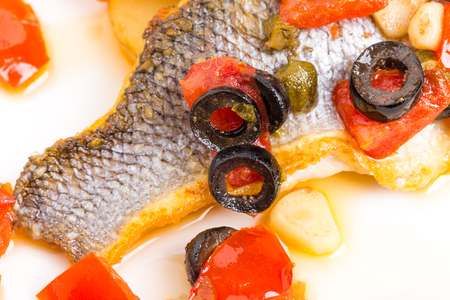 Fillet of seabass on a baked potato with capers and tomatoes. Macro. Photo can be used as a whole background.の写真素材