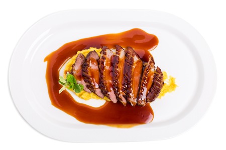 Delicious grilled duck breast on mango puree covered with red sauce. Isolated on a white background.の写真素材