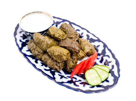 Traditional eastern appetizer dolma stuffed with rice and meat. Served with sour cream sauce and fresh vegetables. Isolated on a white background.の写真素材
