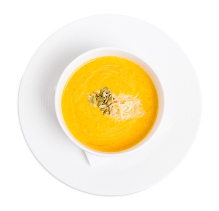 Pumpkin cream soup with grated cheese and seeds. Isolated on a white background.の写真素材