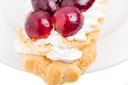 Classic eclair filled with custard and sliced red grapes. Macro. Photo can be used as a whole...