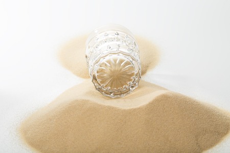 Glass full of ocean sand. Located on a white background.の写真素材