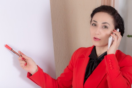 Business woman talking on the phone near the whiteboard.  Photo can be used as a whole background.の写真素材