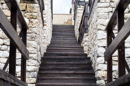 Wooden stairs at a castle. Steps on the top between a rough walling.