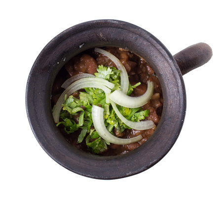 Clay pot full of georgian red beans and grated walnuts. Isolated on a white background.