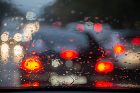 Road view through car window with rain drops. Blurred picture.