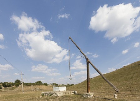 Beautiful country landscape. Old well in country next to power line.の写真素材