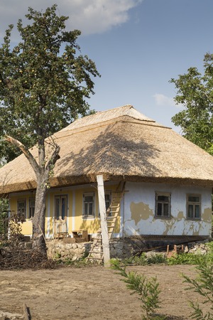 Traditional moldovian rural house. House is under roofing from bulrush and an old pear.の写真素材