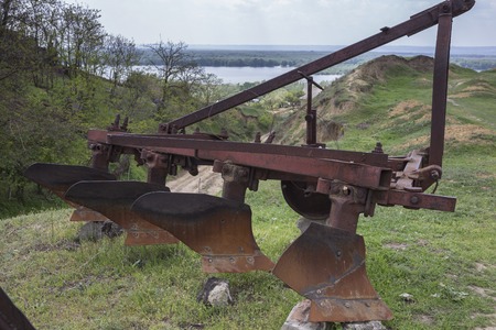 Old rusty plow. This plow is located on top of a hill. Behind the plow is located the canyon and the lake.の写真素材