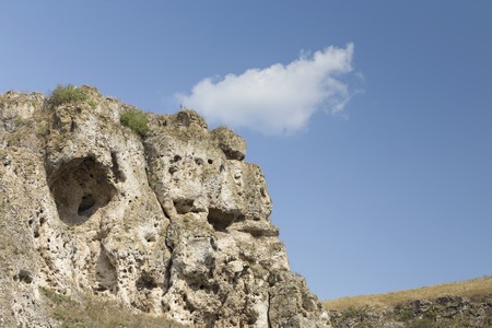 Cliff rock and a white cloud. Reef deposits in the Northof the Republic of Moldova.の写真素材