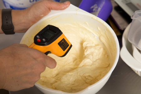 Measuring the temperature of chocolate in a bowl. Special infrared thermometer. Close-up.