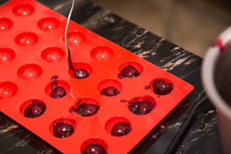 Unfolding the filling in a silicone mold. The process of making chocolates with filling. Close-up.
