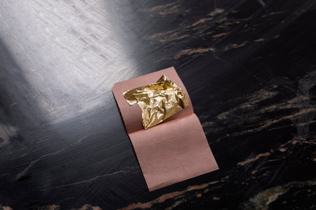 Gold leaf and patch of reflected light. All this is located on a black granite countertop. Close-up.