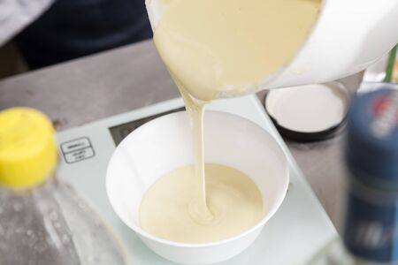 The process of transfusion of melted white chocolate for weighing.Close-up.の写真素材