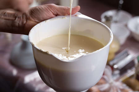 Add the liqued ingredient to the cream bowl. Close-up.の写真素材