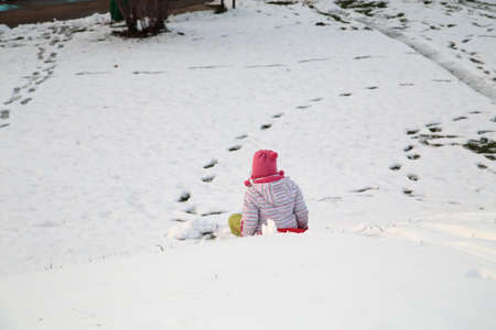 A child on a sled goes down a snow slide. Close-up.の写真素材