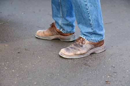 Man's legs in blue denim jeans and brown boots. Close-up.