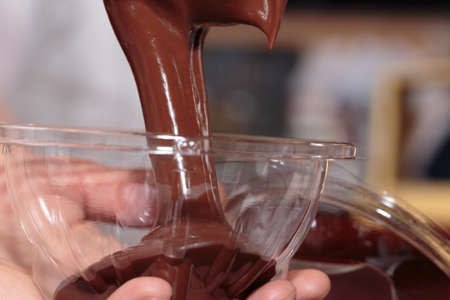 Pouring dark melted chocolate in a glass bowl. Close-up.の写真素材