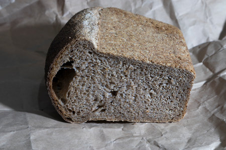Bread baked from whole grain flour. For its baking, a collectible wheat variety Spelta neglectum was used. It is located on wrapping paper. Close-up.の写真素材