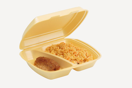 Cutlet and rice in a plastic box for delivery. Isolated over white background. Close-up.の写真素材