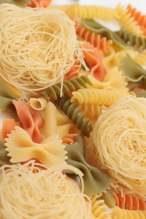 Tricolor macaroni of different types. It is located on a white surface. Close-up.の写真素材