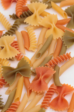 Tricolor macaroni of different types. It is located on a white surface. Close-up.の写真素材