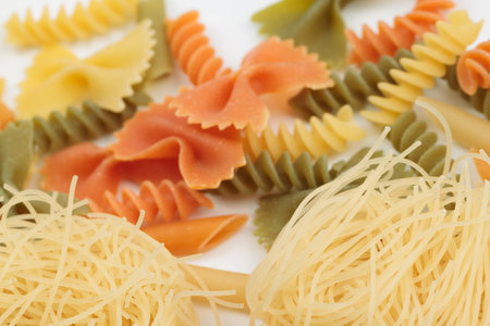 Tricolor macaroni of different types. It is located on a white surface. Close-up.の写真素材