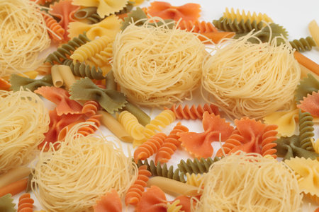 Tricolor macaroni of different types. It is located on a white surface. Close-up.の写真素材
