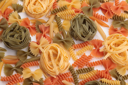 Tricolor macaroni of different types. It is located on a white surface. Close-up.の写真素材