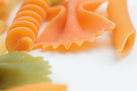 Tricolor macaroni of different types. It is located on a white surface. Close-up.の写真素材