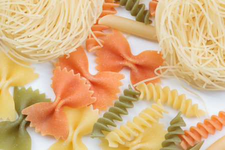 Tricolor macaroni of different types. It is located on a white surface. Close-up.の写真素材