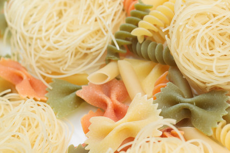 Tricolor macaroni of different types. It is located on a white surface. Close-up.の写真素材