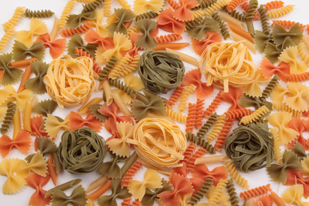 Tricolor macaroni of different types. It is located on a white surface. Close-up.の写真素材