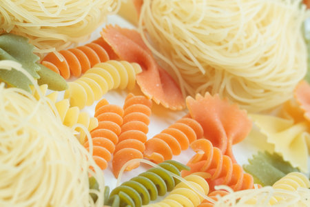 Tricolor macaroni of different types. It is located on a white surface. Close-up.の写真素材