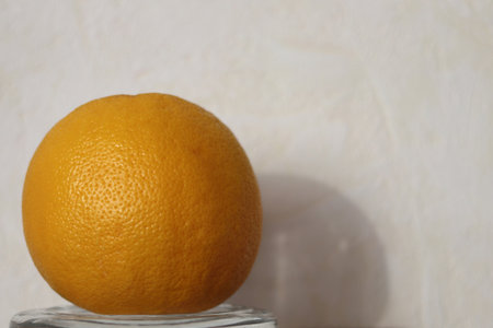 Ripe orange on a crystal stand. A shadow on a light wall. Close-up.の写真素材