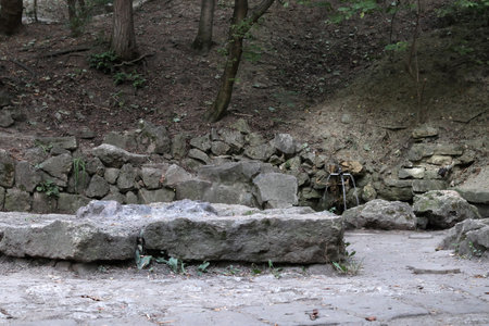 A spring among the stones in a forest. The spring is equipped with steel pipes and stone baths.の写真素材