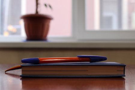 Workplace near a window with a notebook and a pen. Copy space. Modern a desk near window at office. Morning time with warm light. Business concept.の写真素材