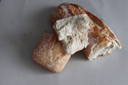 A broken freshly baked rustic baguette. It is located on a gray background. Close-up.の写真素材